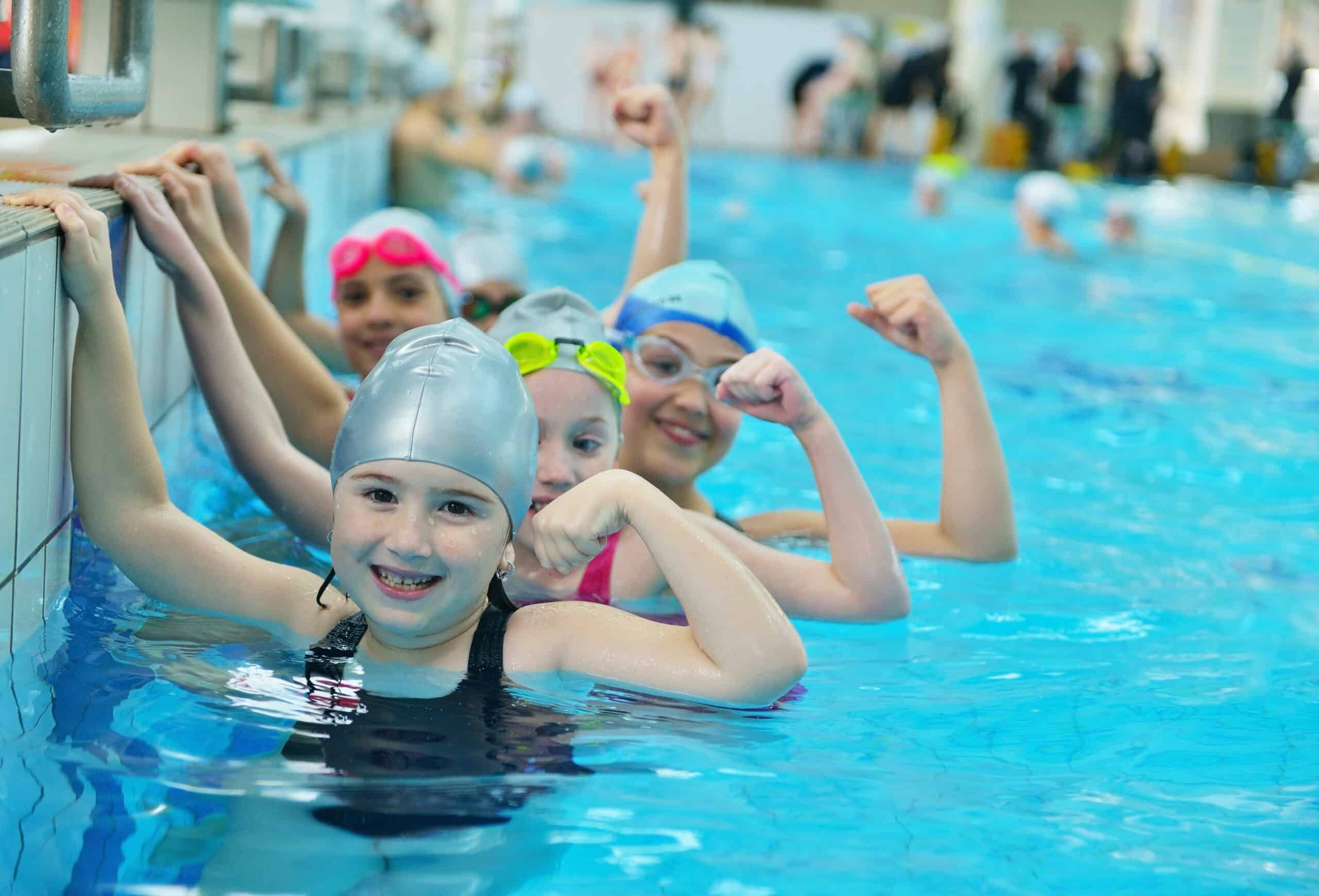 Happy children kids group at swimming pool class learning to swim