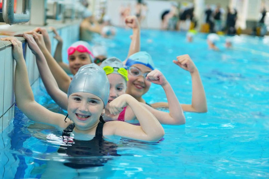 Happy children kids group at swimming pool class learning to swim